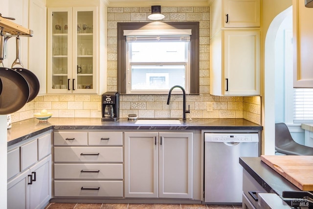 kitchen featuring dark countertops, glass insert cabinets, white cabinets, and dishwasher