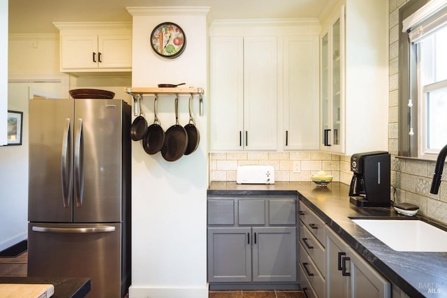 kitchen featuring glass insert cabinets, gray cabinets, and freestanding refrigerator