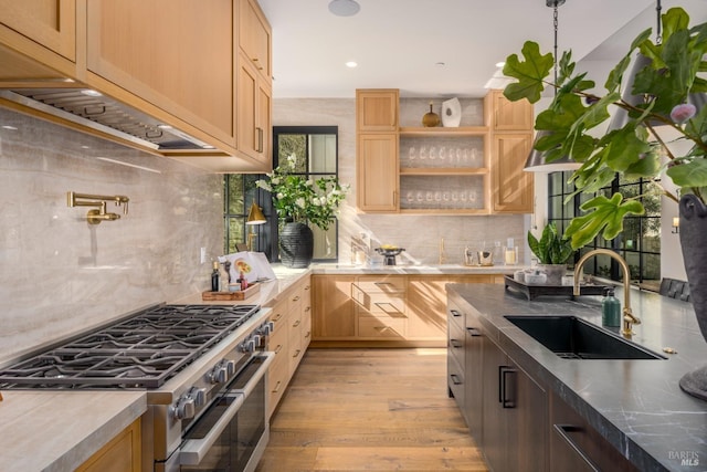 kitchen featuring light wood-type flooring, double oven range, a sink, and light brown cabinetry