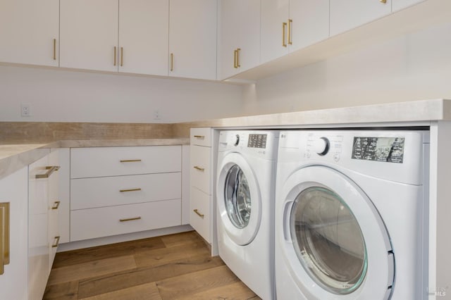 washroom featuring wood finished floors, cabinet space, and washer and dryer