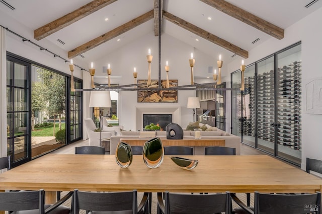 interior space with high vaulted ceiling, beam ceiling, a glass covered fireplace, and visible vents