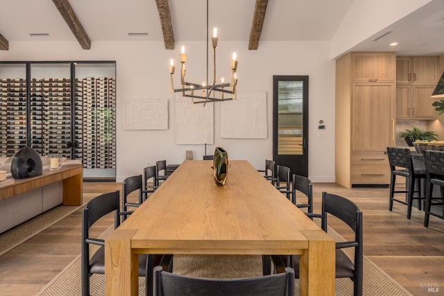 dining area with a chandelier, beam ceiling, visible vents, and light wood-style flooring