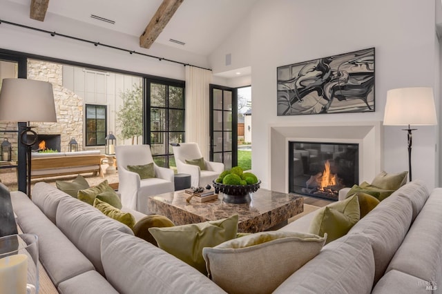 living area with high vaulted ceiling, a glass covered fireplace, visible vents, and beamed ceiling