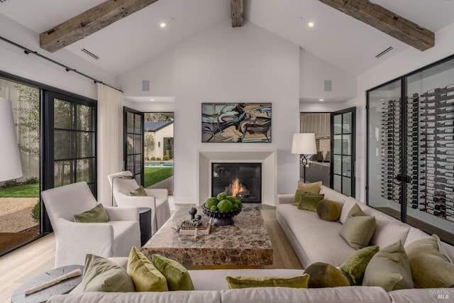 living area featuring visible vents, beam ceiling, and a glass covered fireplace