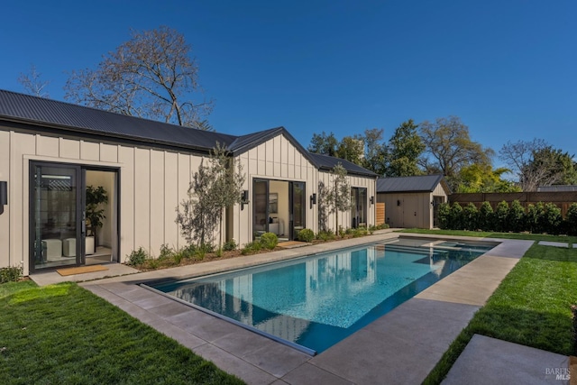 back of property with metal roof, a yard, board and batten siding, and a fenced in pool