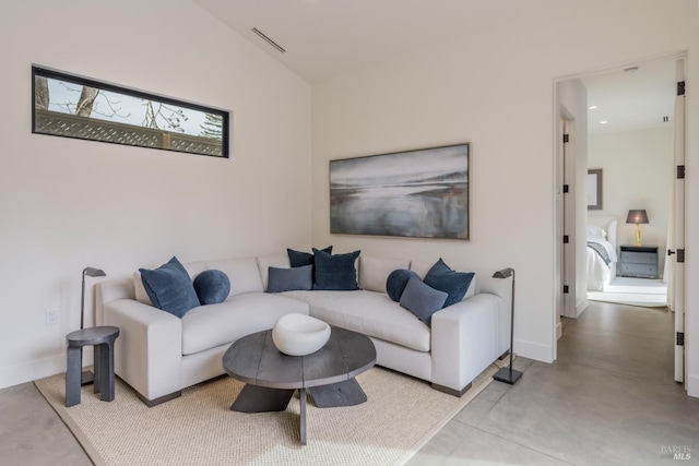 living room with concrete flooring, vaulted ceiling, visible vents, and baseboards