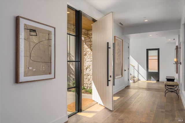 hall with stairway, wood-type flooring, visible vents, and recessed lighting