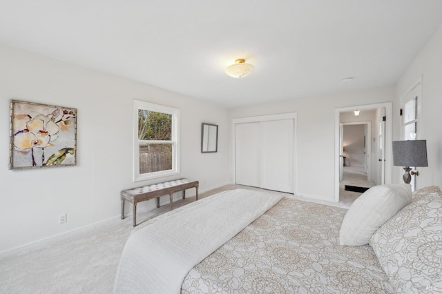 bedroom featuring light carpet, baseboards, and a closet