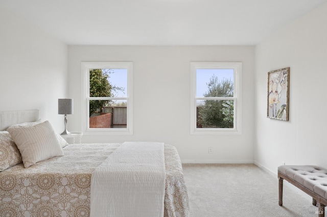 bedroom featuring light carpet, multiple windows, and baseboards