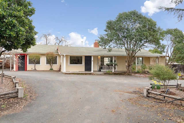 ranch-style house featuring driveway and a chimney