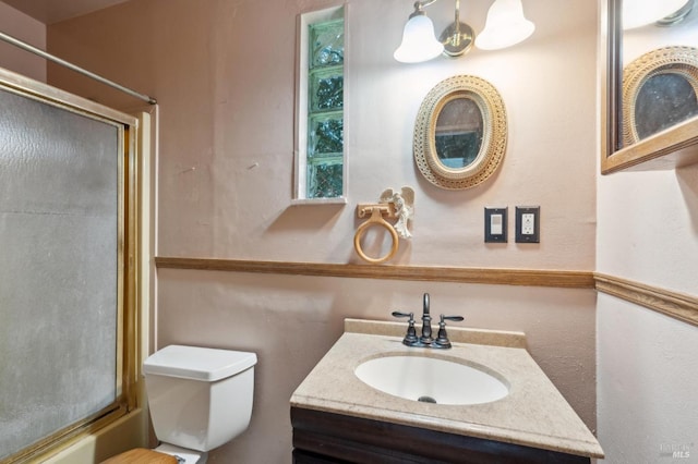 full bath with combined bath / shower with glass door, vanity, and toilet