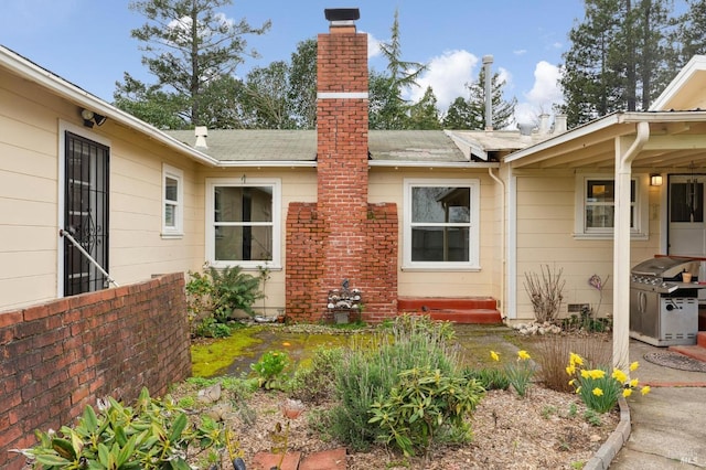 property entrance with a shingled roof and a chimney