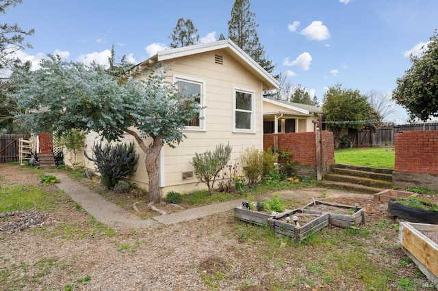 view of home's exterior featuring a vegetable garden and fence