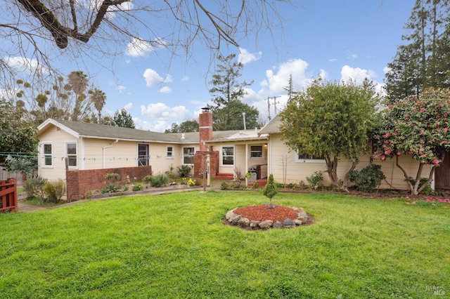 view of front of home with brick siding, fence, a chimney, and a front lawn