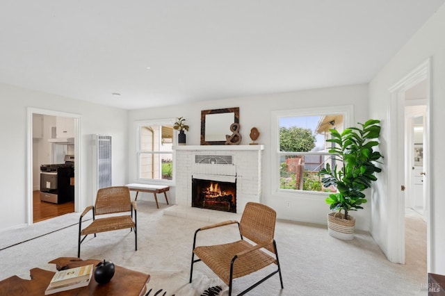 living area featuring a brick fireplace, light colored carpet, and plenty of natural light