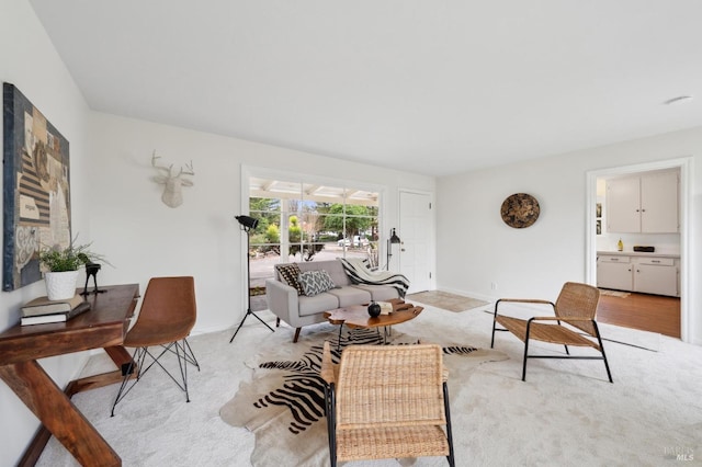 living area featuring light carpet and baseboards