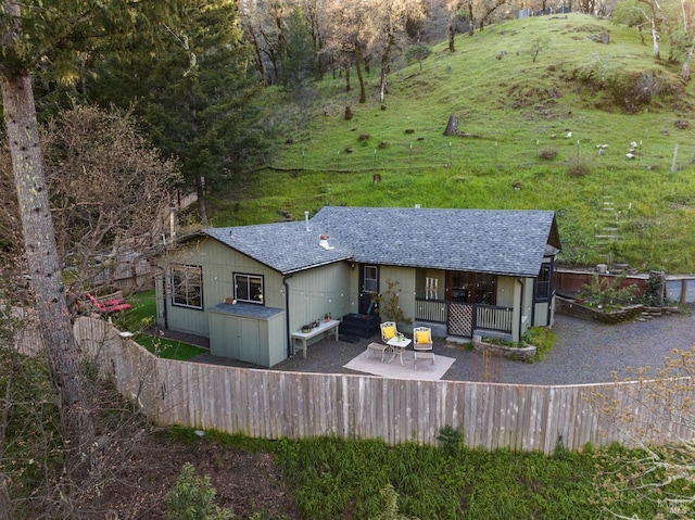 view of front of property with roof with shingles, a front lawn, and a patio