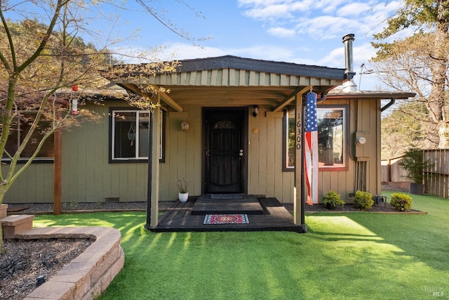 view of exterior entry with a yard and fence