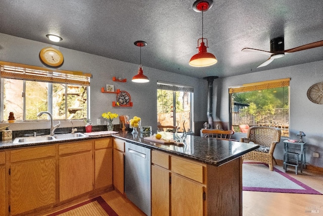 kitchen featuring a peninsula, a sink, light wood-style floors, dishwasher, and a wood stove