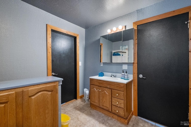 bathroom with a textured wall, tile patterned flooring, and vanity