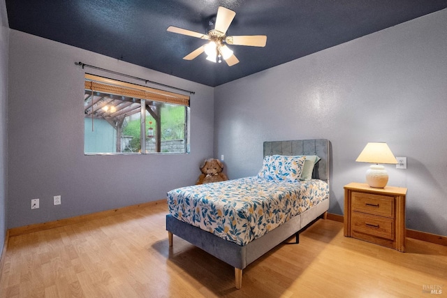 bedroom with ceiling fan, baseboards, and wood finished floors