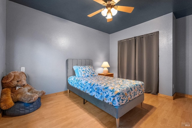 bedroom featuring a ceiling fan, baseboards, and wood finished floors