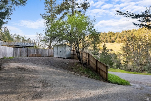 view of yard with fence private yard, a storage shed, and an outbuilding