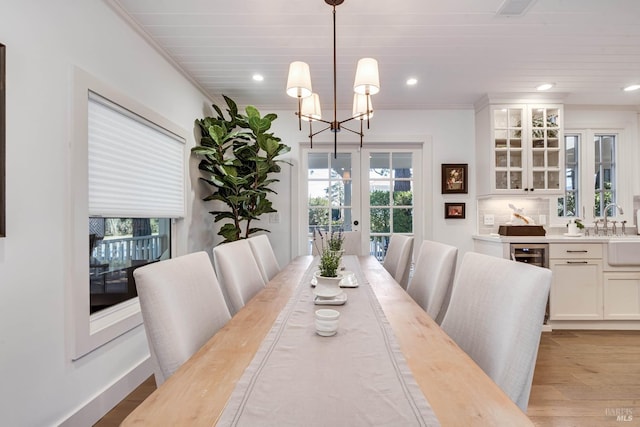 dining area with french doors, a notable chandelier, crown molding, recessed lighting, and light wood-style floors