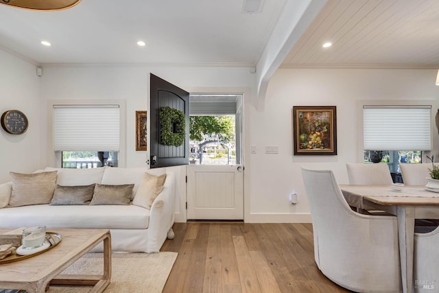 living room featuring plenty of natural light, crown molding, and light wood finished floors