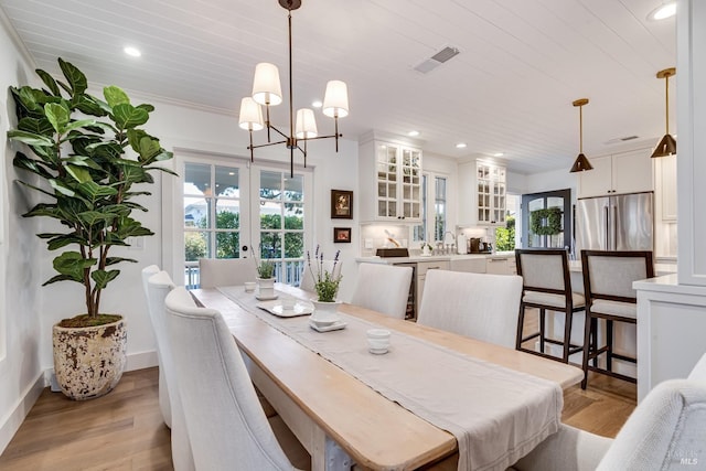 dining room featuring light wood-style floors, plenty of natural light, visible vents, and french doors