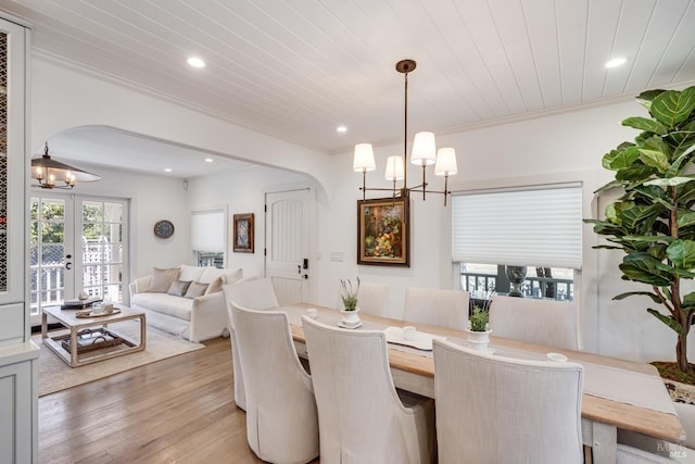 dining area featuring arched walkways, light wood-style flooring, an inviting chandelier, ornamental molding, and wood ceiling