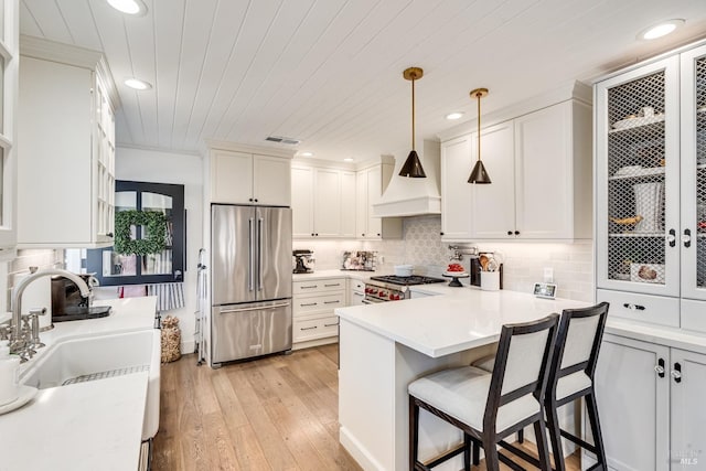 kitchen featuring custom exhaust hood, visible vents, white cabinetry, high quality appliances, and a peninsula