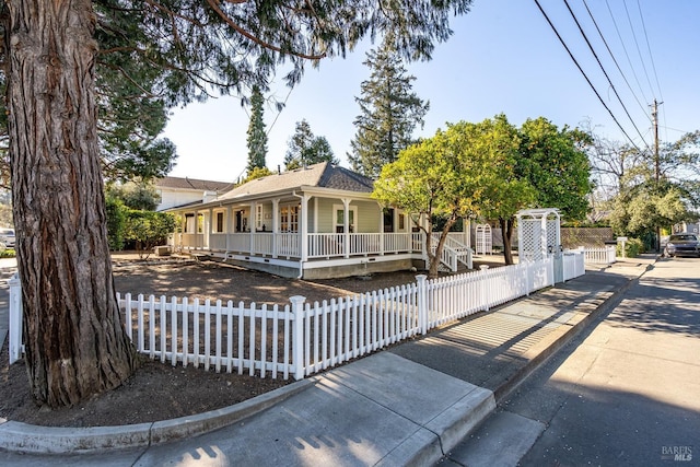 view of front facade featuring a fenced front yard, a porch, and roof with shingles