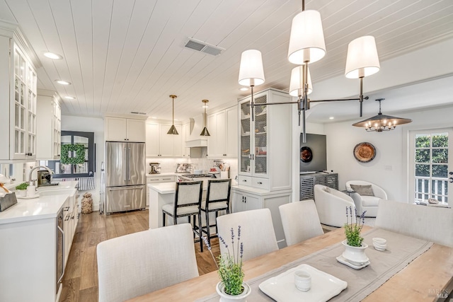 dining room featuring visible vents, light wood-type flooring, wooden ceiling, and recessed lighting