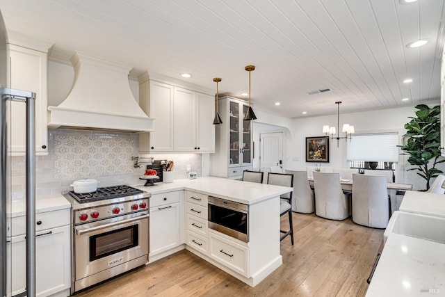 kitchen with light countertops, premium range hood, premium stove, and visible vents