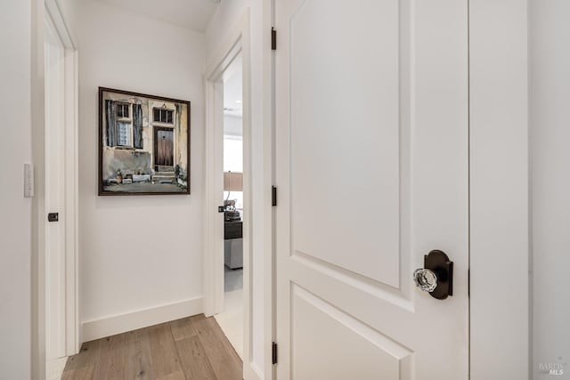 corridor with light wood-style flooring and baseboards