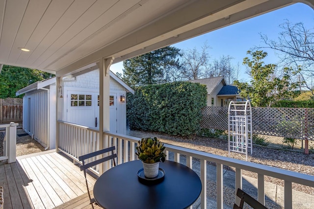 deck with a storage shed, outdoor dining area, an outdoor structure, and fence