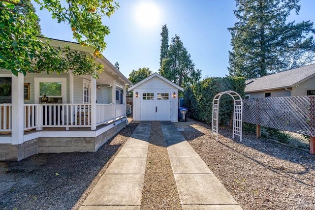 view of home's exterior featuring a shed, fence, a porch, and an outbuilding