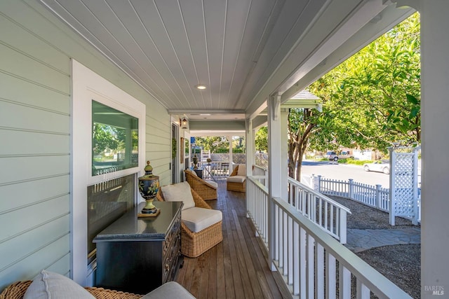 wooden terrace featuring covered porch and fence