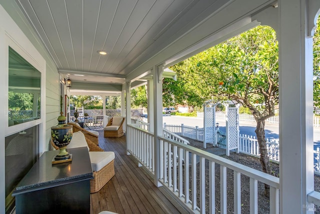 wooden deck featuring covered porch and fence