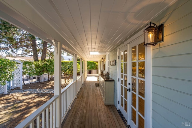 wooden deck with covered porch, fence, and french doors