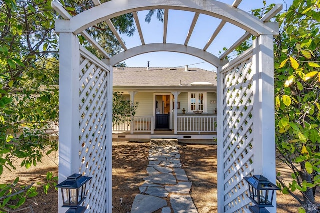 entrance to property featuring a porch and a shingled roof