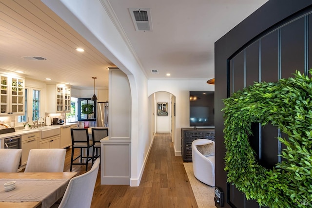 interior space with arched walkways, light wood-style flooring, recessed lighting, visible vents, and ornamental molding