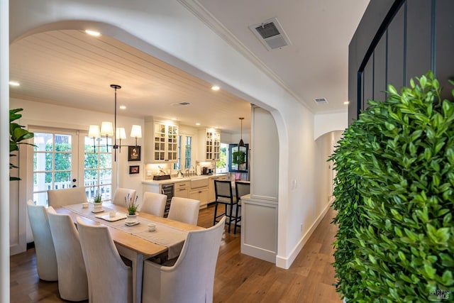 dining area featuring arched walkways, wood finished floors, visible vents, and crown molding