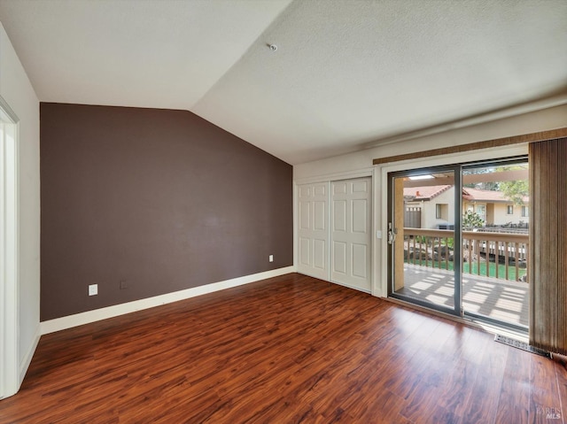 unfurnished bedroom featuring wood finished floors, baseboards, vaulted ceiling, access to outside, and a closet