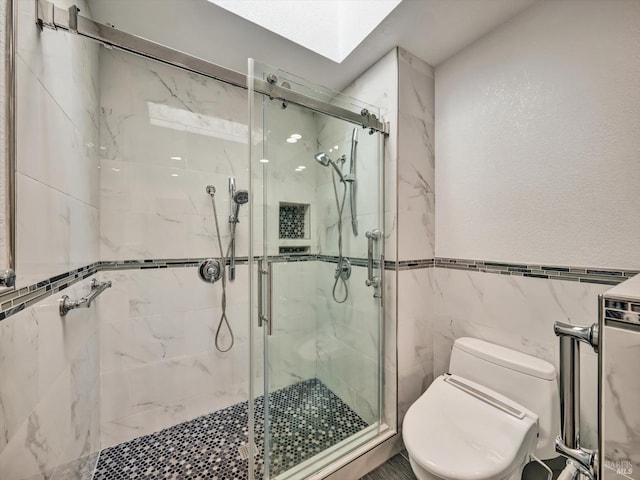 full bath featuring a skylight, a marble finish shower, tile walls, and toilet