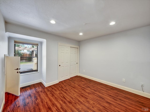 unfurnished room featuring baseboards, visible vents, wood finished floors, a textured ceiling, and recessed lighting