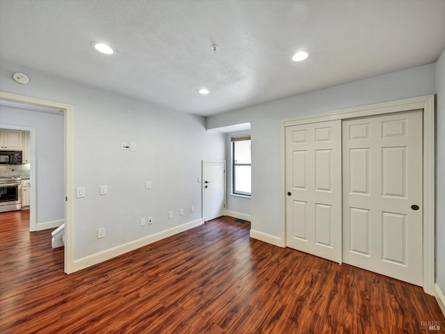 unfurnished bedroom with recessed lighting, a closet, dark wood finished floors, and baseboards