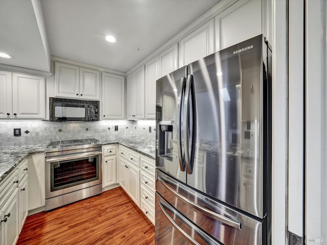 kitchen with stainless steel appliances, white cabinetry, and backsplash