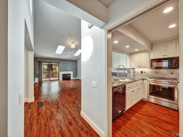 kitchen with black appliances, tasteful backsplash, a sink, and dark wood finished floors